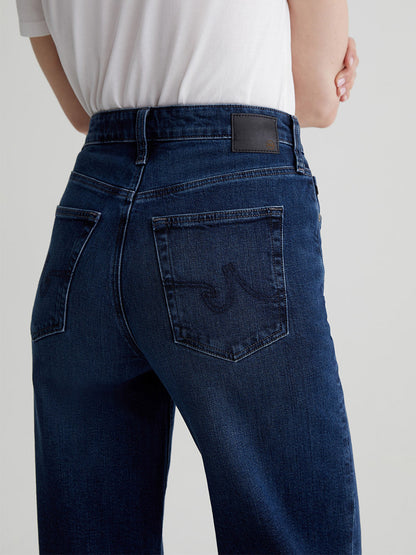 A person is wearing the AG Jeans Kora High-Rise Wide Leg in Midnight Sun, featuring dark blue jeans paired with a crisp white shirt, and viewed from the back.