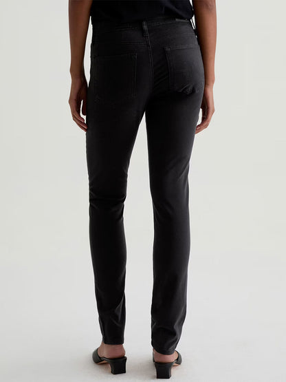 Model wears the AG Jeans Prima Cigarette Leg in Super Black with black open-toe shoes, shown from the back against a plain light background.