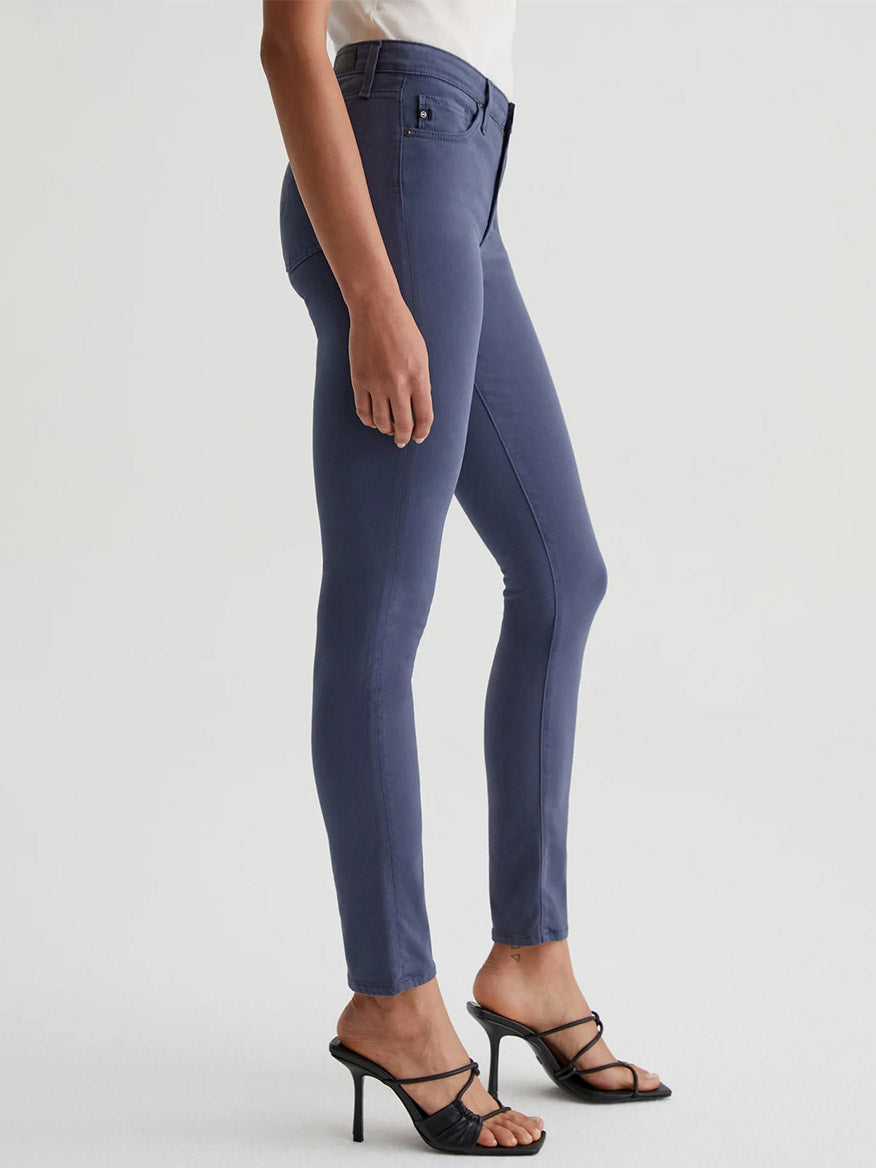 The model is wearing a pair of AG Jeans Prima Cigarette Leg in Blue Note with a fitted silhouette.