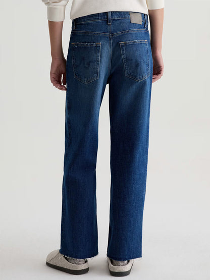 A person is shown from the back wearing AG Jeans Saige Wide Leg Crop in Watermist, paired with a light sweater and gray slip-on shoes against a plain background.