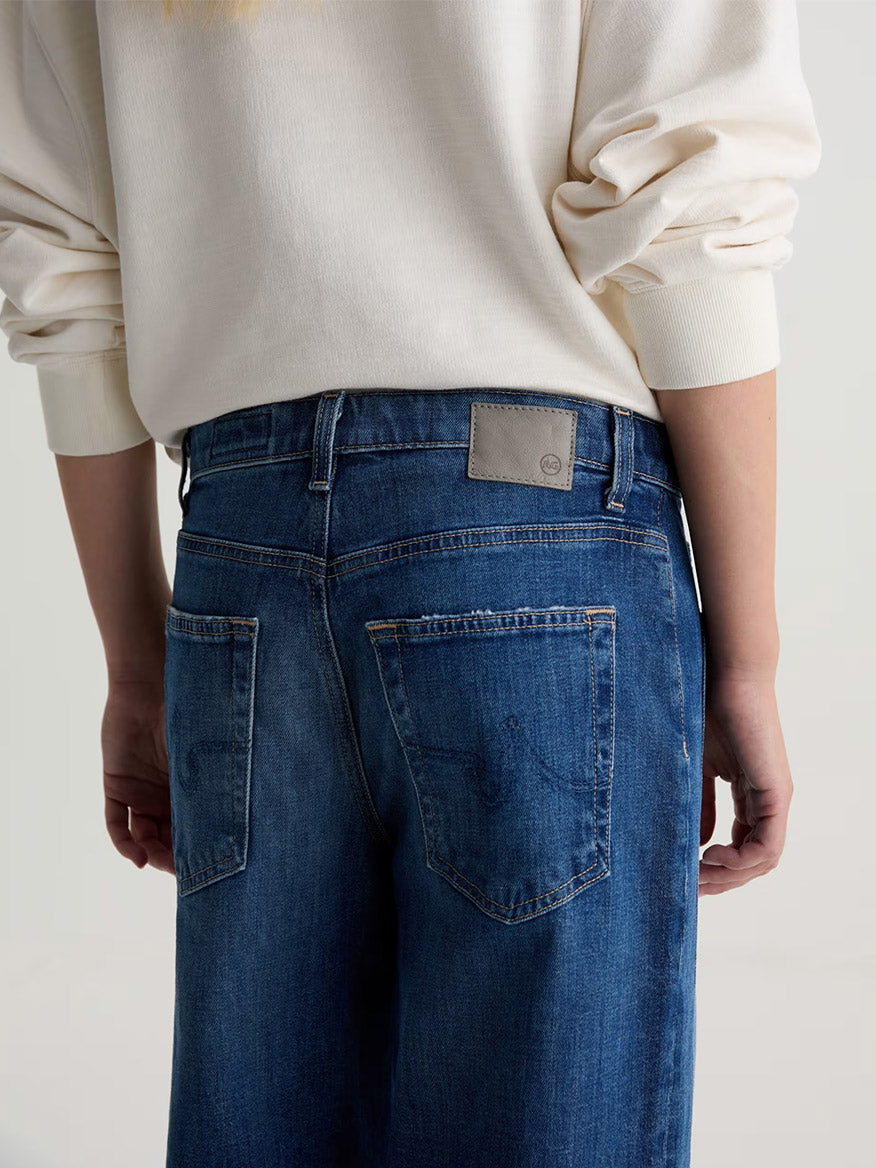 Person shown from the back, wearing a cream long-sleeve top and AG Jeans Saige Wide Leg Crop in Watermist, with hands at their sides.