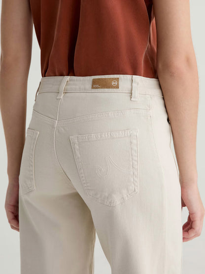 A person wearing a rust-colored shirt and AG Jeans Saige Wide Leg Crop With Panel in Opal Stone, shown from the back, featuring visible pockets and belt loops.