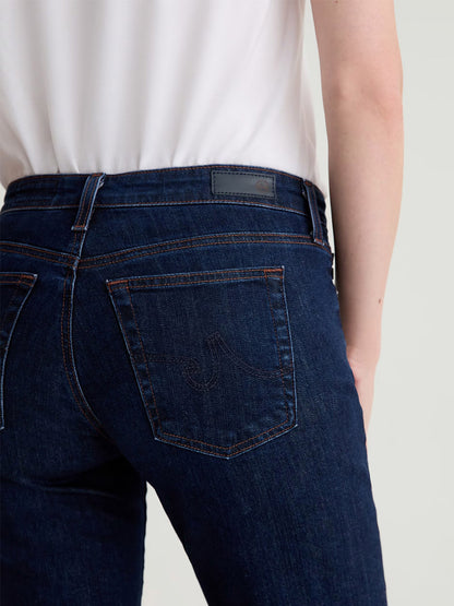 A person wearing AG Jeans Sandra Low-Rise Straight in Modern Indigo and a white top, photographed from the waist down and viewed from behind.