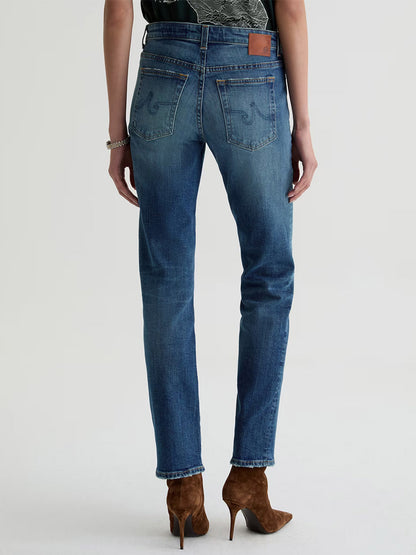 Model wears AG Jeans Sandra Low-Rise Straight in 10 Years Illiad, styled with brown heeled boots. Shown from the back against a plain light background.