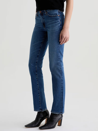 Someone wearing AG Jeans Sandra AG-ed™ Low-Rise Straight in 15 Years Prague, a black top, and black heeled ankle boots stands against a plain light background.