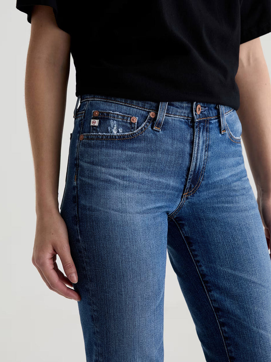 A person is wearing a black short-sleeve shirt and AG Jeans Sandra AG-ed™ Low-Rise Straight in 15 Years Prague, shown from waist to mid-thigh against a plain background.