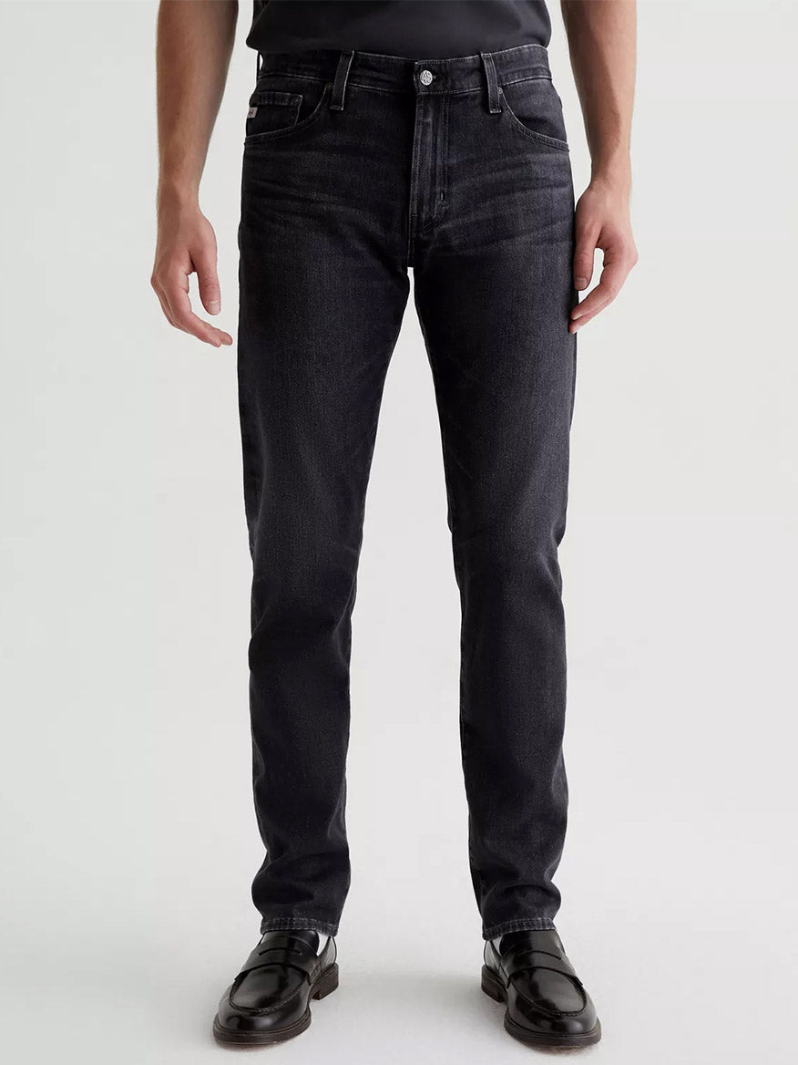 A man standing in front of a white background wearing AG-ed black AG Jeans Tellis in 13 Years Curtis.