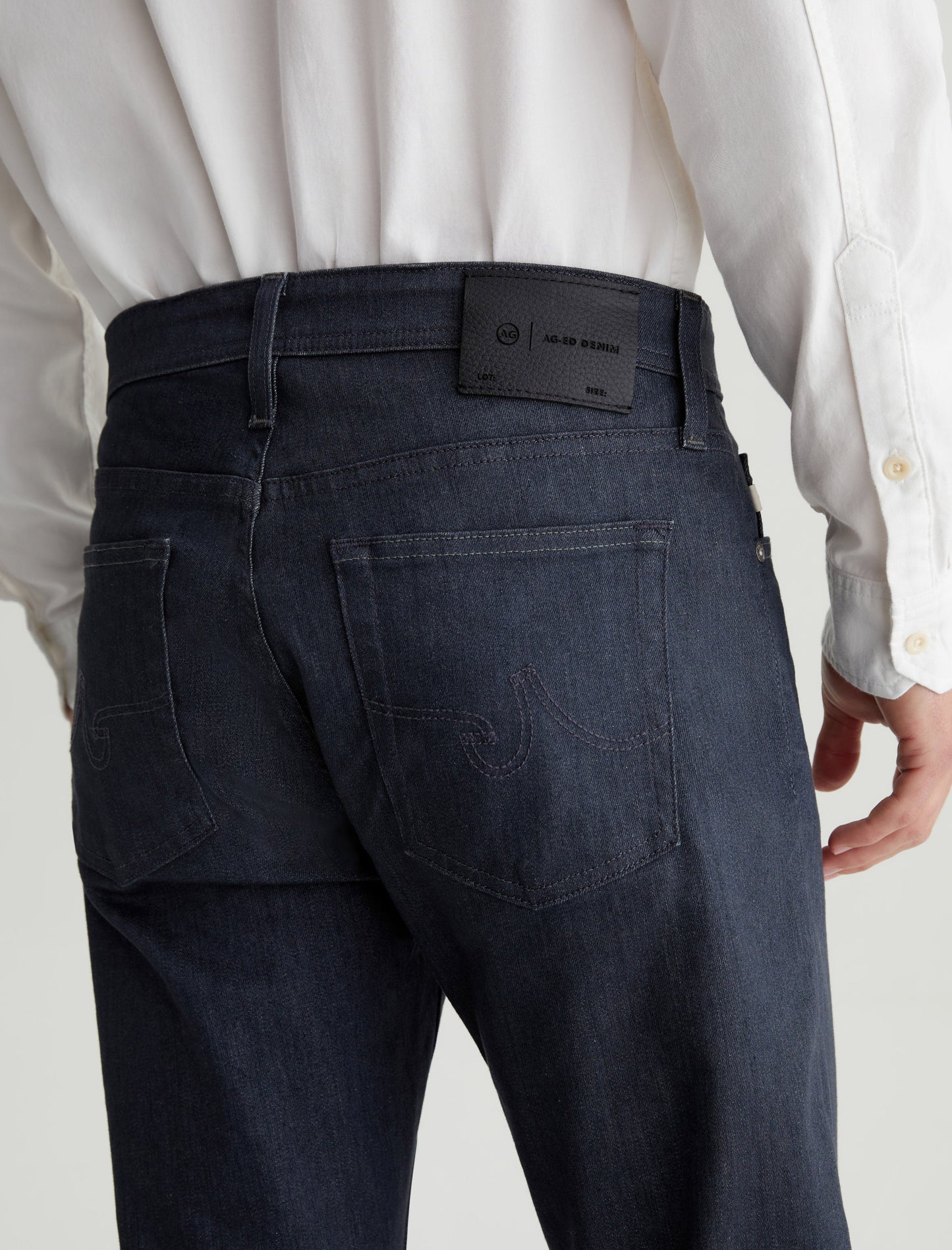 A person wearing a white shirt and AG Jeans Tellis in 1 Year Reel, photographed from the back.