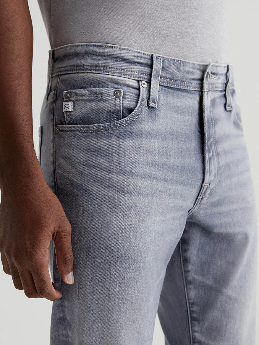 Close-up of a person wearing AG Jeans Tellis in Vapor Wash Atwater, focusing on the upper part with a hand resting lightly on the hip.