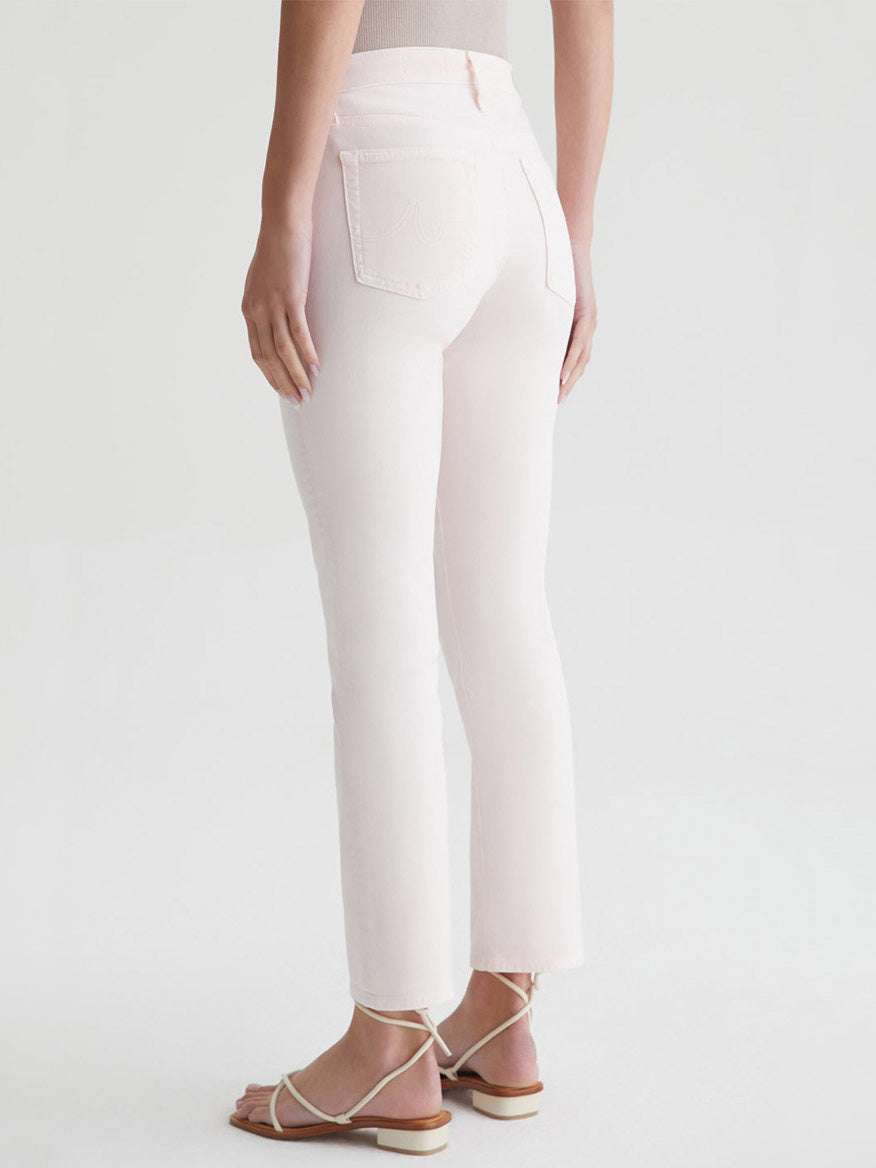 Woman standing in AG Jeans Mari High Rise Slim Straight in Sulfur Soft Blush and sandals, view from behind waist-down.