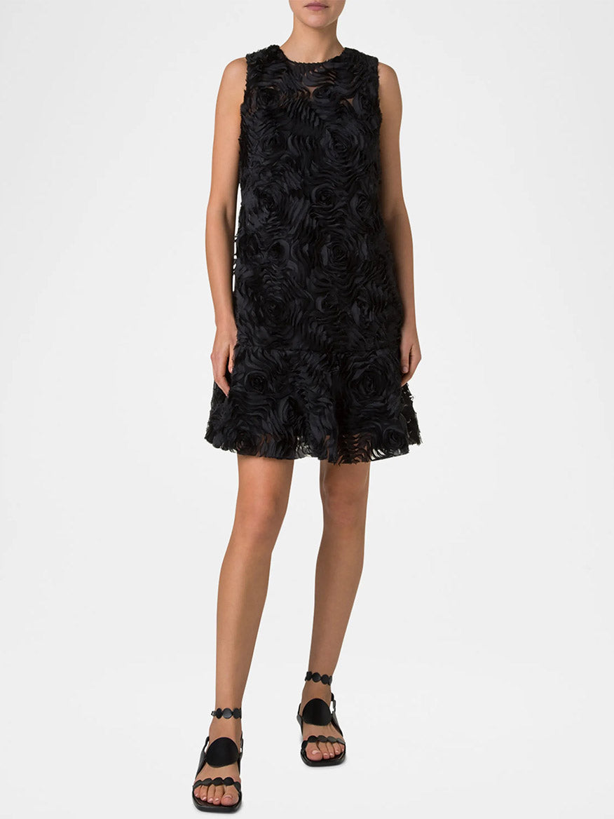 On a plain white background, a person wears the elegant Akris Punto Sleeveless 3D Carnation Knee Length Dress in black, paired with black sandals.