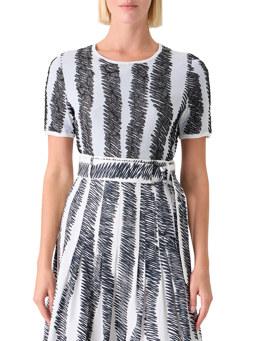 A woman wearing the Akris Punto 3D Scribble Jacquard Knit Sweater in Cream/Black, featuring short sleeves and bold zigzag patterns, shown from mid-torso up.