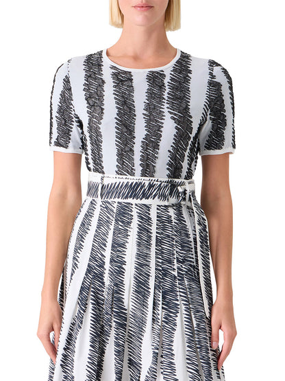 A woman wearing the Akris Punto 3D Scribble Jacquard Knit Sweater in Cream/Black, featuring short sleeves and bold zigzag patterns, shown from mid-torso up.