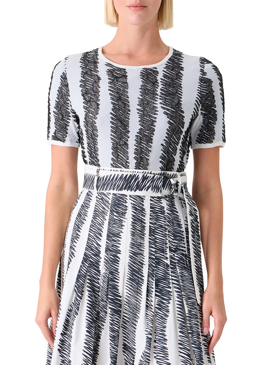 A woman wearing the Akris Punto 3D Scribble Jacquard Knit Sweater in Cream/Black, featuring short sleeves and bold zigzag patterns, shown from mid-torso up.