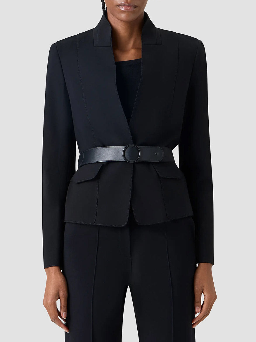 A person wearing the Akris Punto Belted Jacket in Black, paired with black pants and a black top, photographed from the waist up against a plain background.