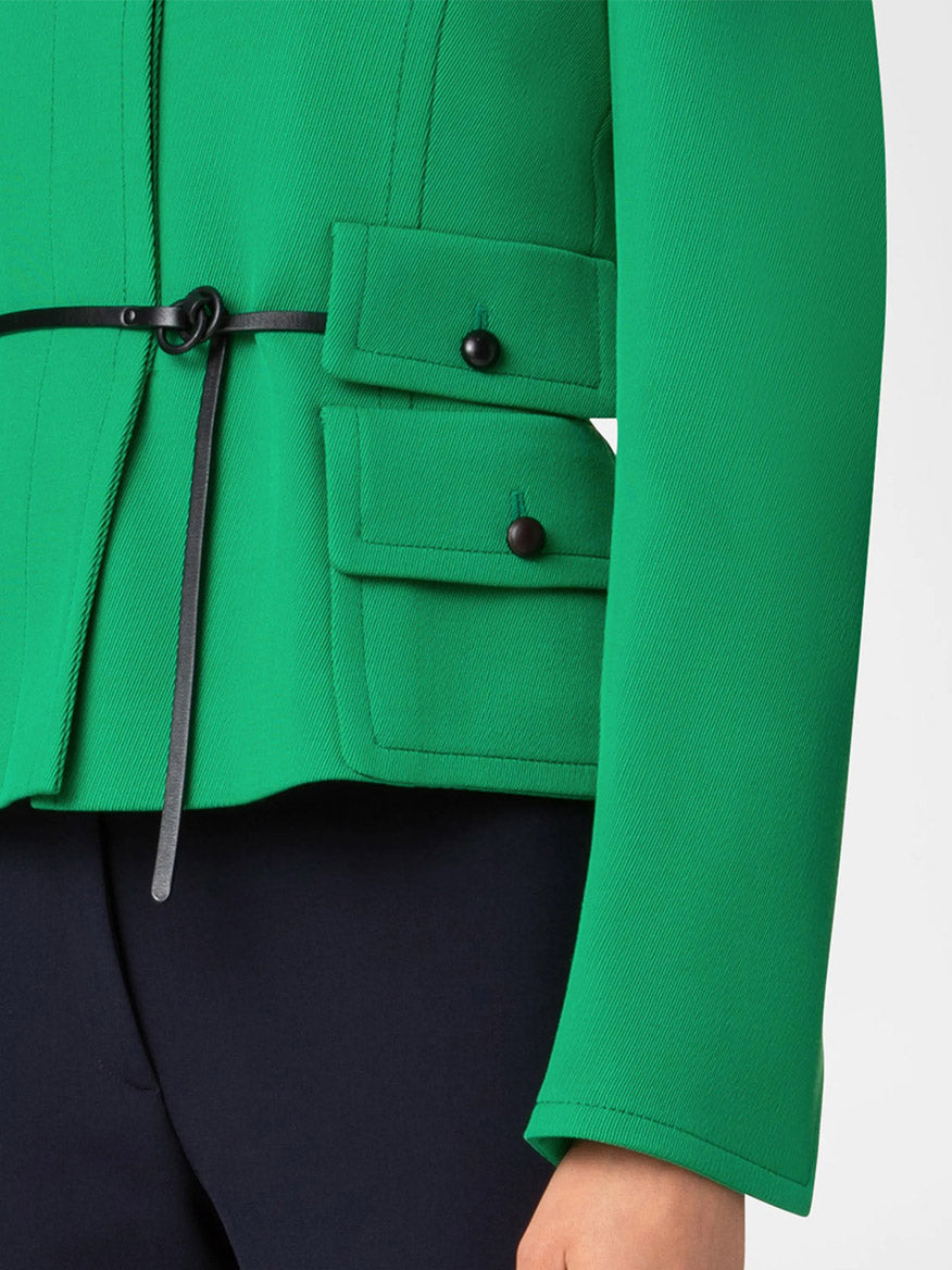 Close-up of the Akris Punto Fitted Belted Tricotine Jacket in Sea Green/Navy, featuring black buttoned pockets and a drawstring detail, paired with black pants.