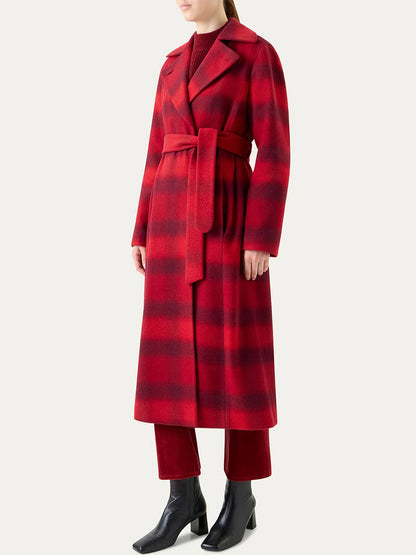 A person wears the Akris Punto Blurred Check Belted Double-Breasted Coat in Cranberry/Blackberry, styled with red pants, a red top, and black ankle boots, standing against a plain light background.