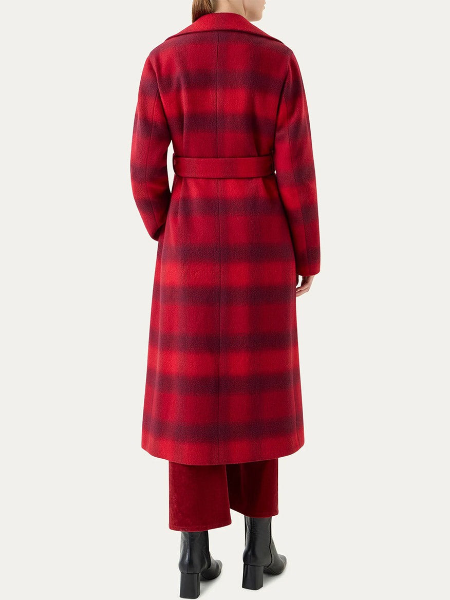 A person shown from the back wears the Akris Punto Blurred Check Belted Double-Breasted Coat in Cranberry/Blackberry, paired with red pants and black boots.