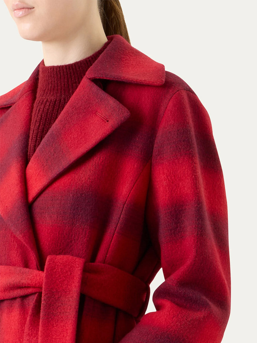 A woman wears the Akris Punto Blurred Check Belted Double-Breasted Coat in Cranberry/Blackberry over a maroon sweater, shown from shoulders to waist against a plain background.