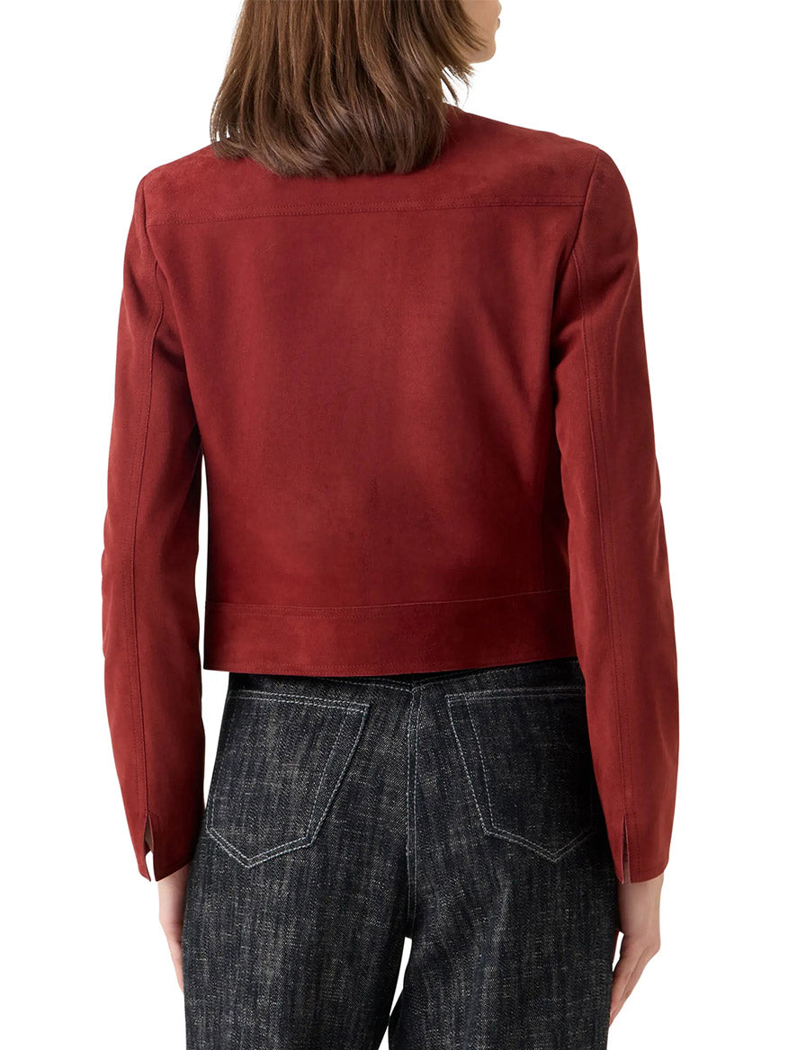 A person with shoulder-length brown hair is seen from the back wearing the Akris Punto Boxy Suede Jacket in Pomegranate and dark jeans, set against a white background.