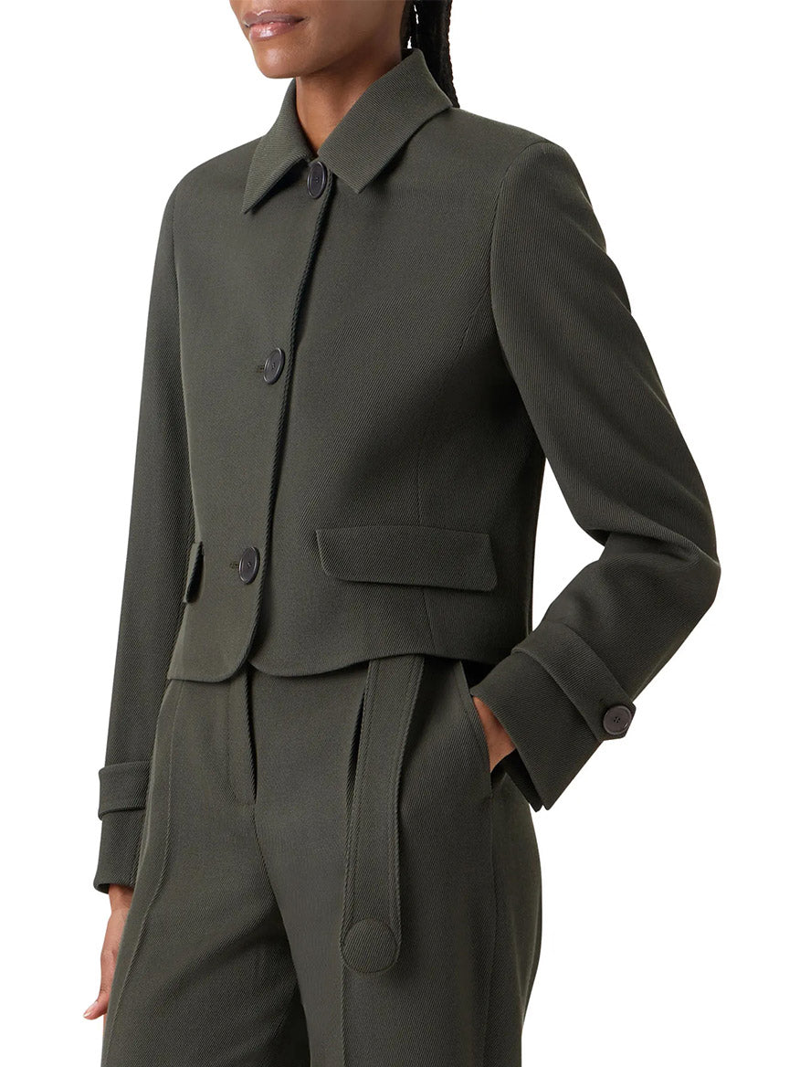 A person wearing the Akris Punto Boxy Wool Tricotine Jacket in Olive, featuring large buttons, decorative pocket flaps, and paired with matching high-waisted pants.