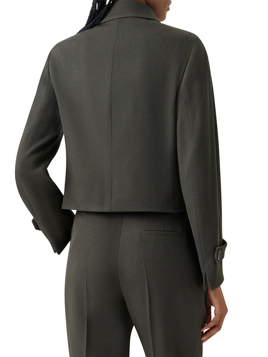 A person is seen from the back wearing the Akris Punto Boxy Wool Tricotine Jacket in Olive, styled as a cropped blazer with decorative pocket flaps and paired with matching straight-leg trousers.