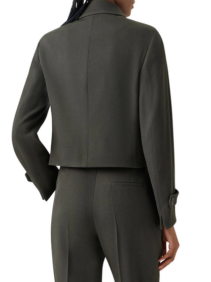 A person is seen from the back wearing the Akris Punto Boxy Wool Tricotine Jacket in Olive, styled as a cropped blazer with decorative pocket flaps and paired with matching straight-leg trousers.