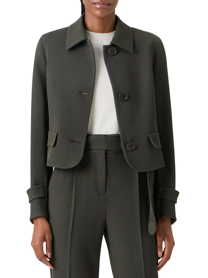 A person wears the Akris Punto Boxy Wool Tricotine Jacket in Olive, featuring decorative pocket flaps and large buttons, paired with matching high-waisted trousers and a white top.