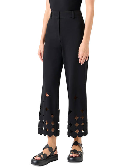 A person wearing Akris Punto Chieko Dropping Dot Cut Out Ankle Pant in black with geometric dot cutouts near the hem and black sandals, standing against a white background.