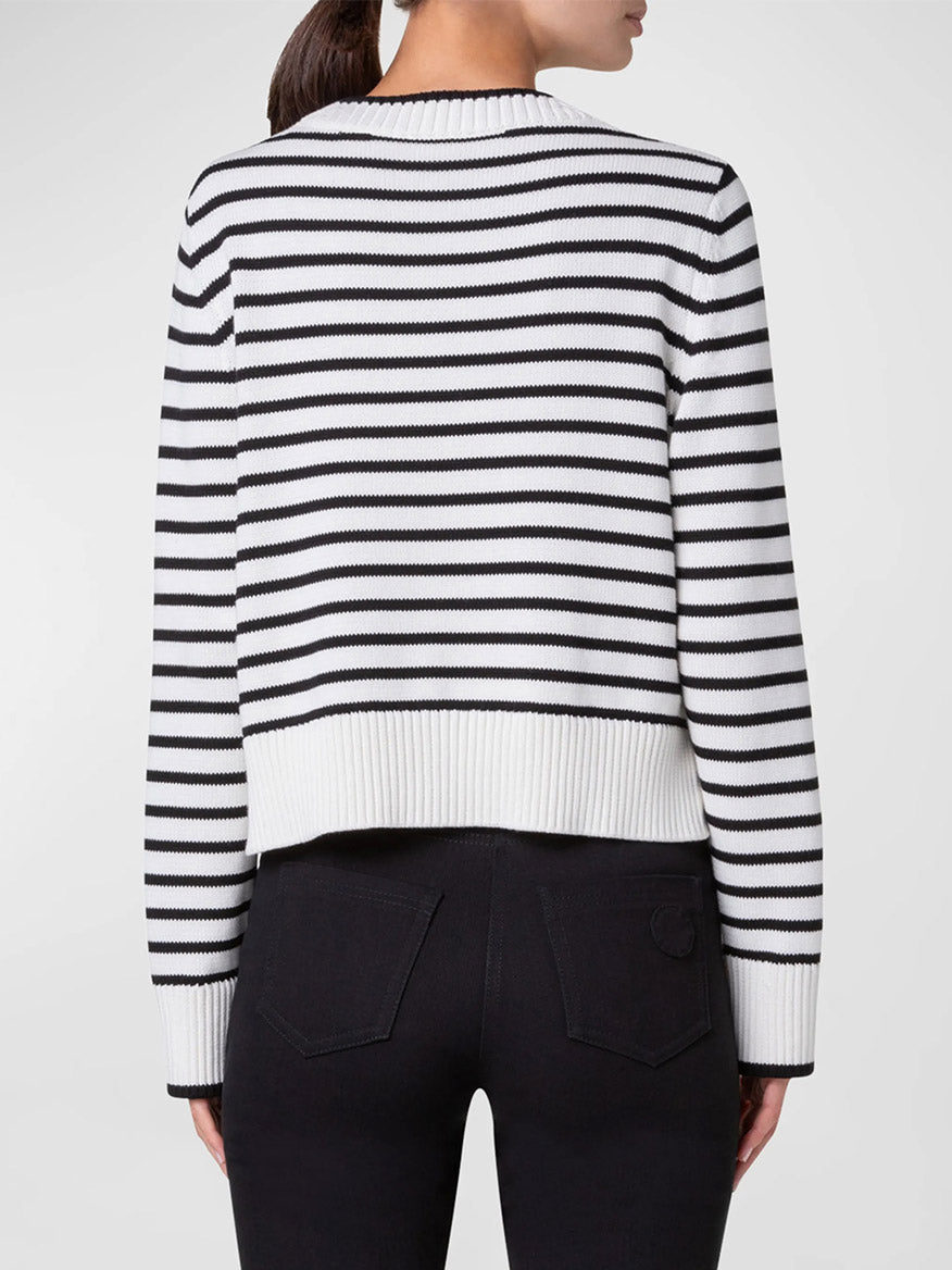 A person wearing the Akris Punto Chunky Cotton Stripe Sweater in Cream/Black with a boxy fit and black pants is shown from the back.