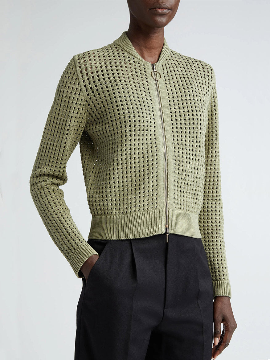 A woman wearing a green knit zip-front Akris Punto Chunky Mesh Bomber Cardigan in Sage.