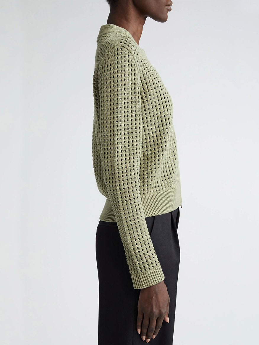 The back view of a woman wearing an Akris Punto Chunky Mesh Bomber Cardigan in Sage.