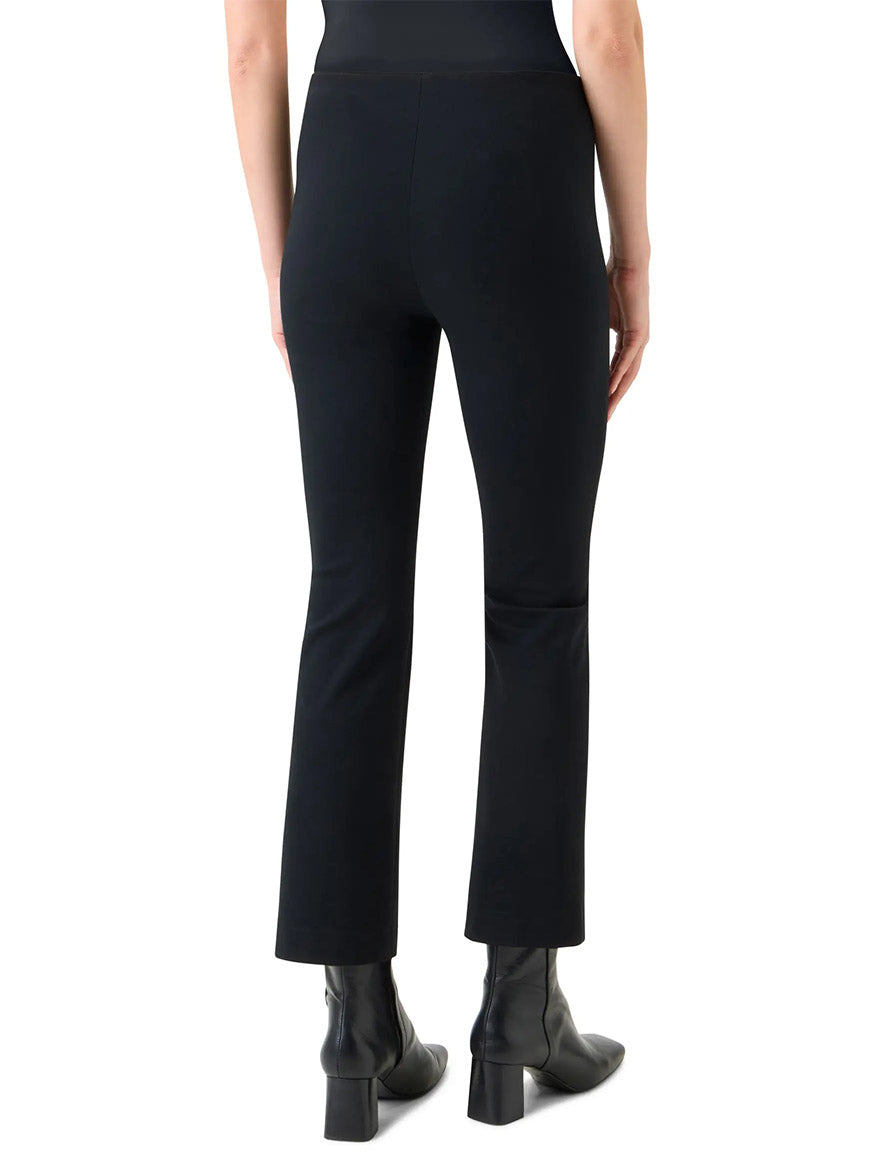 A person wearing the Akris Punto Elements Cindy Cropped Bootcut Pant in Black and black ankle boots with a side zip, viewed from the back against a plain white background.