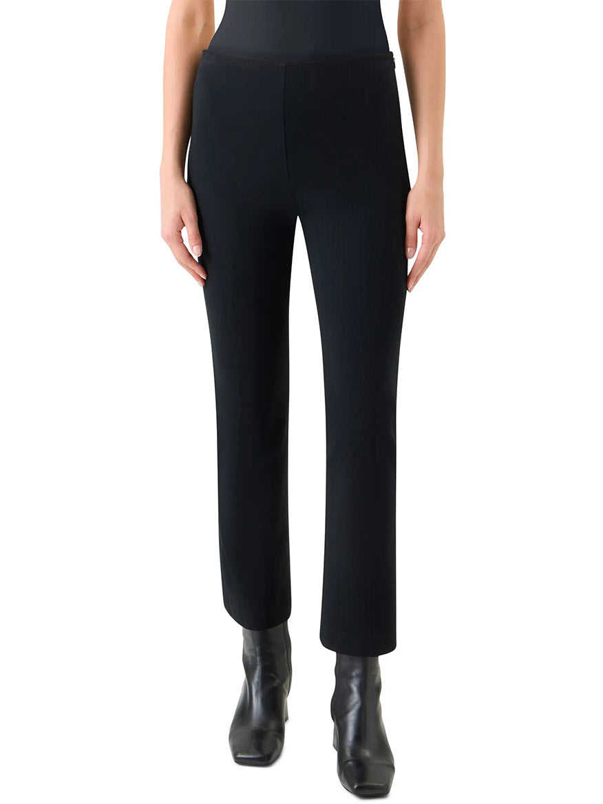 A person wears Akris Punto Elements Cindy Cropped Bootcut Pant in Black with black ankle boots, standing against a plain white background.