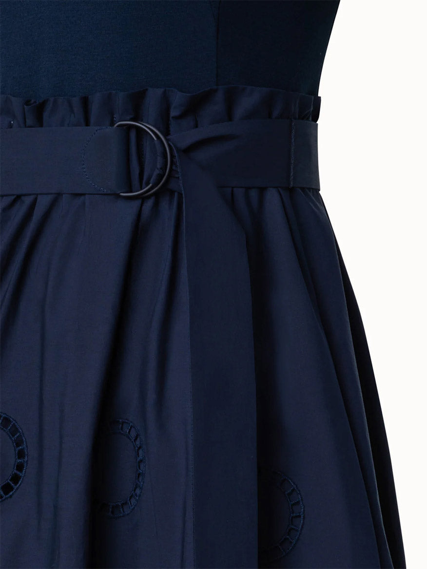 Close-up of a navy blue Akris Punto Fit and Flare Midi Shirt Dress with Circle Eyelets, belt detail, and pocket accents.