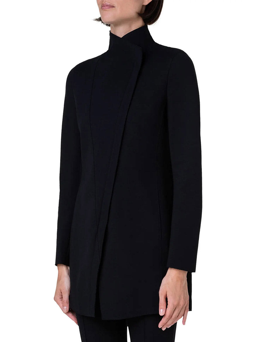 Person wearing a long, high-necked black Akris Punto Jersey Moto Zip Jacket with a minimalist design. The front closure is hidden and the sleeves are long. The background is plain white.