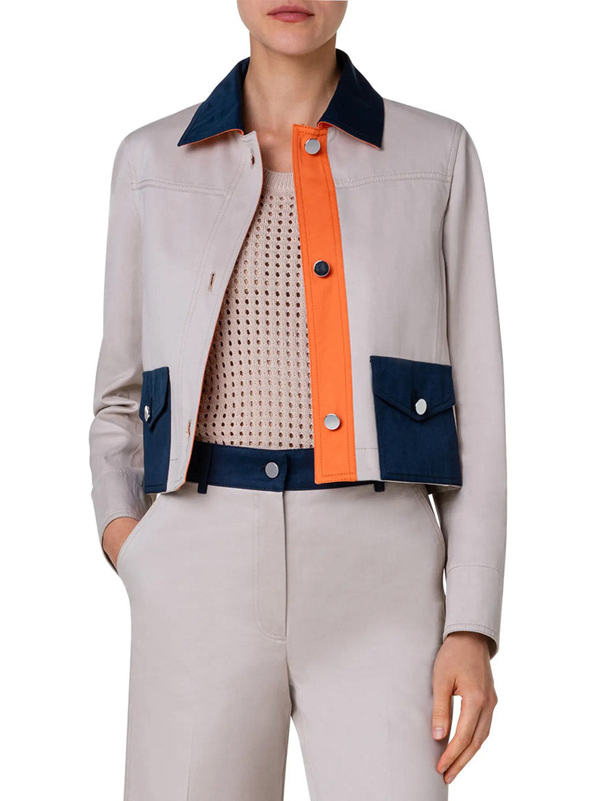 A woman is wearing a cropped version of the Akris Punto Colorblock Crop Jean Jacket in Beige/Navy/Orange.