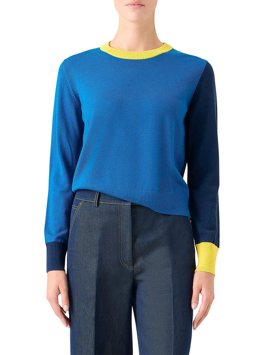 A person wearing the Akris Punto Cool Wool Colorblock Crewneck Sweater in Cobalt Blue Multi with yellow collar and cuffs, paired with high-waisted blue jeans, stands against a plain background.