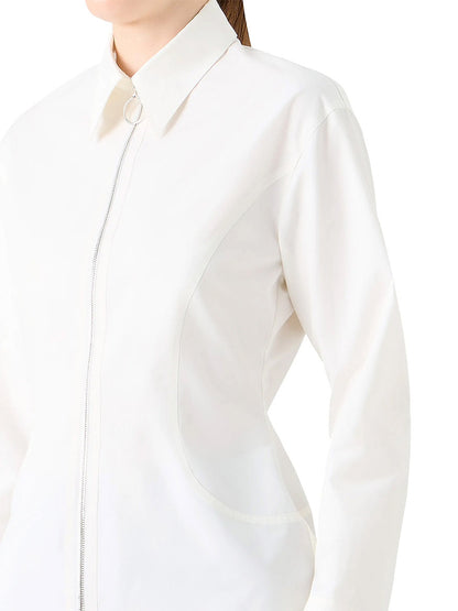 A person wears the Akris Punto Poplin Cotton Cinched Waist Shirt in Cream, featuring long sleeves, a collared neckline, front zipper with a circular pull, and signature brand detailing.