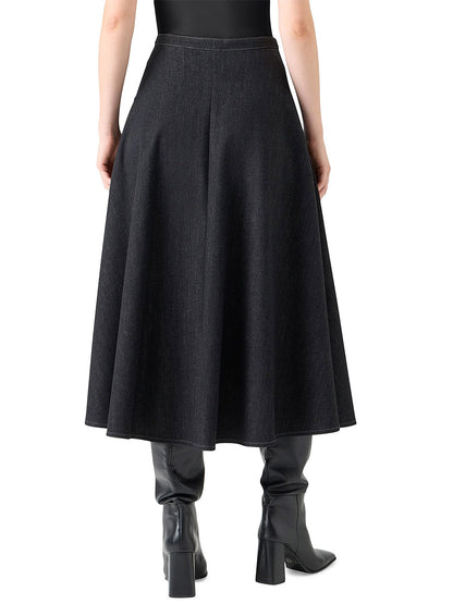 A person is seen from the back wearing an Akris Punto Stretch Denim Snap Button Midi Skirt in Black Denim, paired with an oversized floral shirt and black heeled boots.