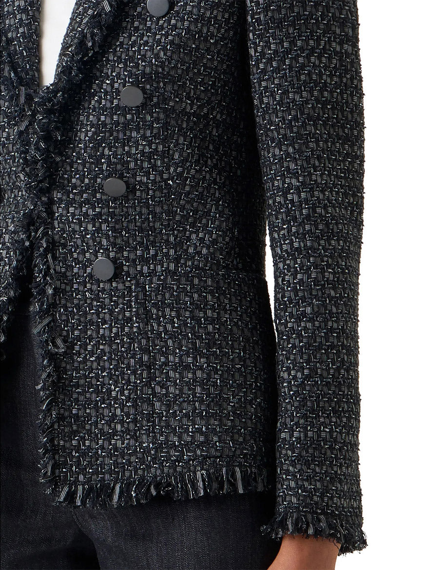 Close-up of a person wearing the Akris Punto Double-Breasted Fringed Tweed Jacket in Black/Stone, featuring a basket-weave pattern, shawl collar, black buttons, frayed edges, and paired with dark pants.