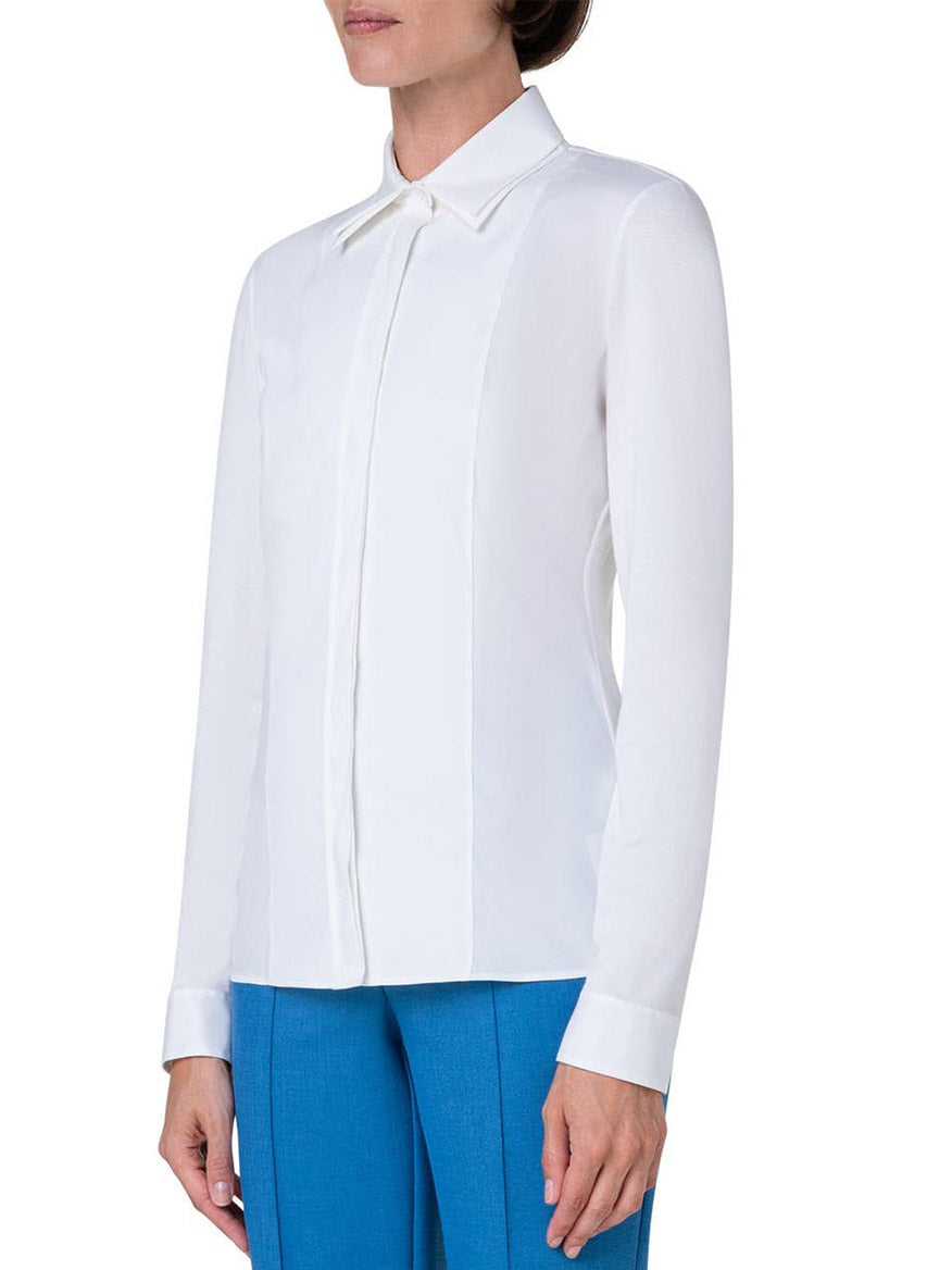A woman, embodying a modern mood, confidently flaunts her Akris Punto Double Collar Jersey Back Shirt in Cream and blue pants.