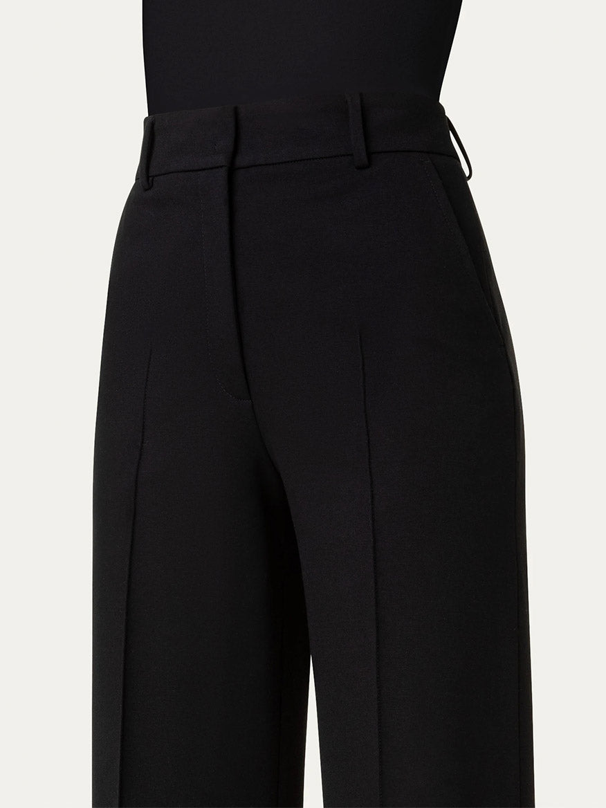 Close-up of a person wearing Akris Punto Chiaro Jersey Straight Leg Pant in Black with belt loops, pockets, and a crease down the front of each leg.