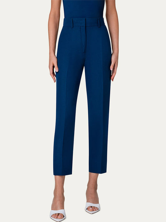 The model is wearing a blue cropped jumpsuit made of linen, featuring a tapered-leg silhouette and Akris Punto Feryn Linen Tapered Pants in Ink.