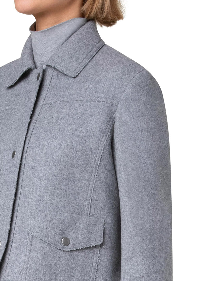 A close-up of a person wearing the Akris Punto Felted Wool Blend Short Patch Pocket Jacket in Grey with a high collar and snap buttons, paired with a light gray turtleneck.