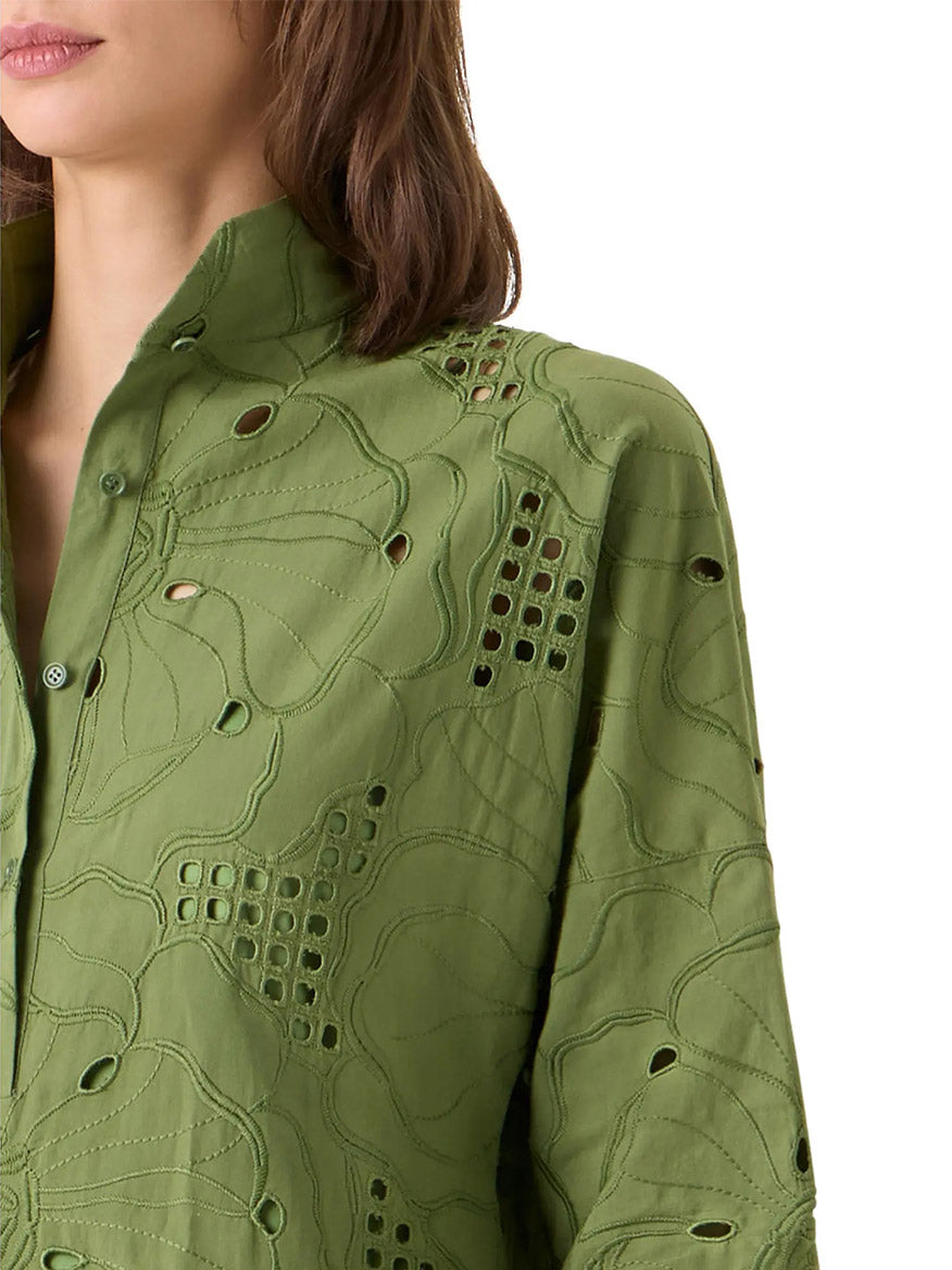 A person wearing the Akris Punto Flower Eyelet Embroidered Handkerchief Dress in Green Tea, featuring cut-out and embroidered eyelet patterns, is shown from shoulders to mid-torso.