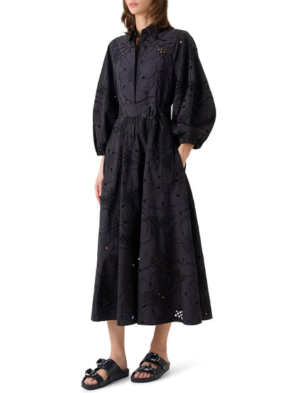 Woman wearing the Akris Punto Flower Eyelet Embroidered Midi Dress in black, paired with flat black sandals, standing against a white background.