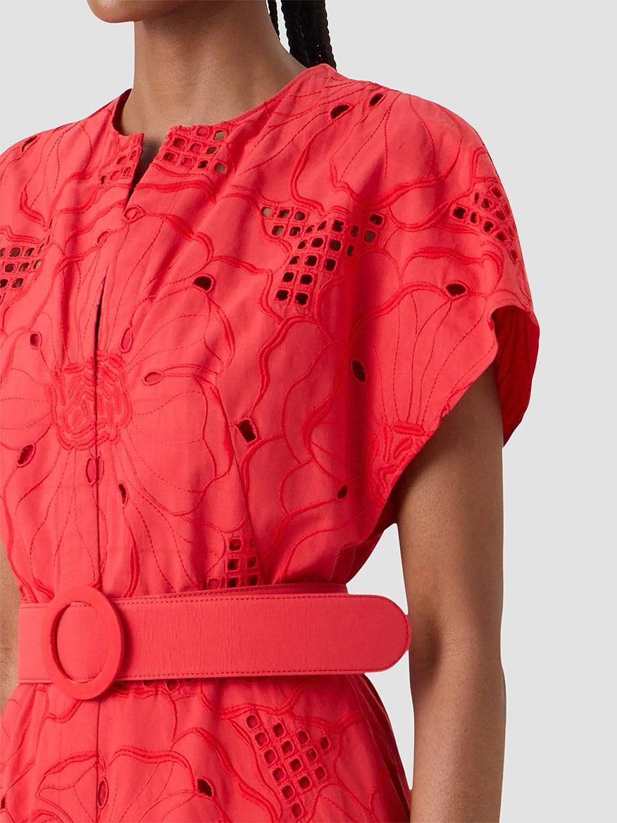 A person wearing the Akris Punto Flower Eyelet Embroidered Midi Dress in Red, featuring floral eyelet embroidery, a matching wide belt, and short sleeves, shown from shoulders to waist.