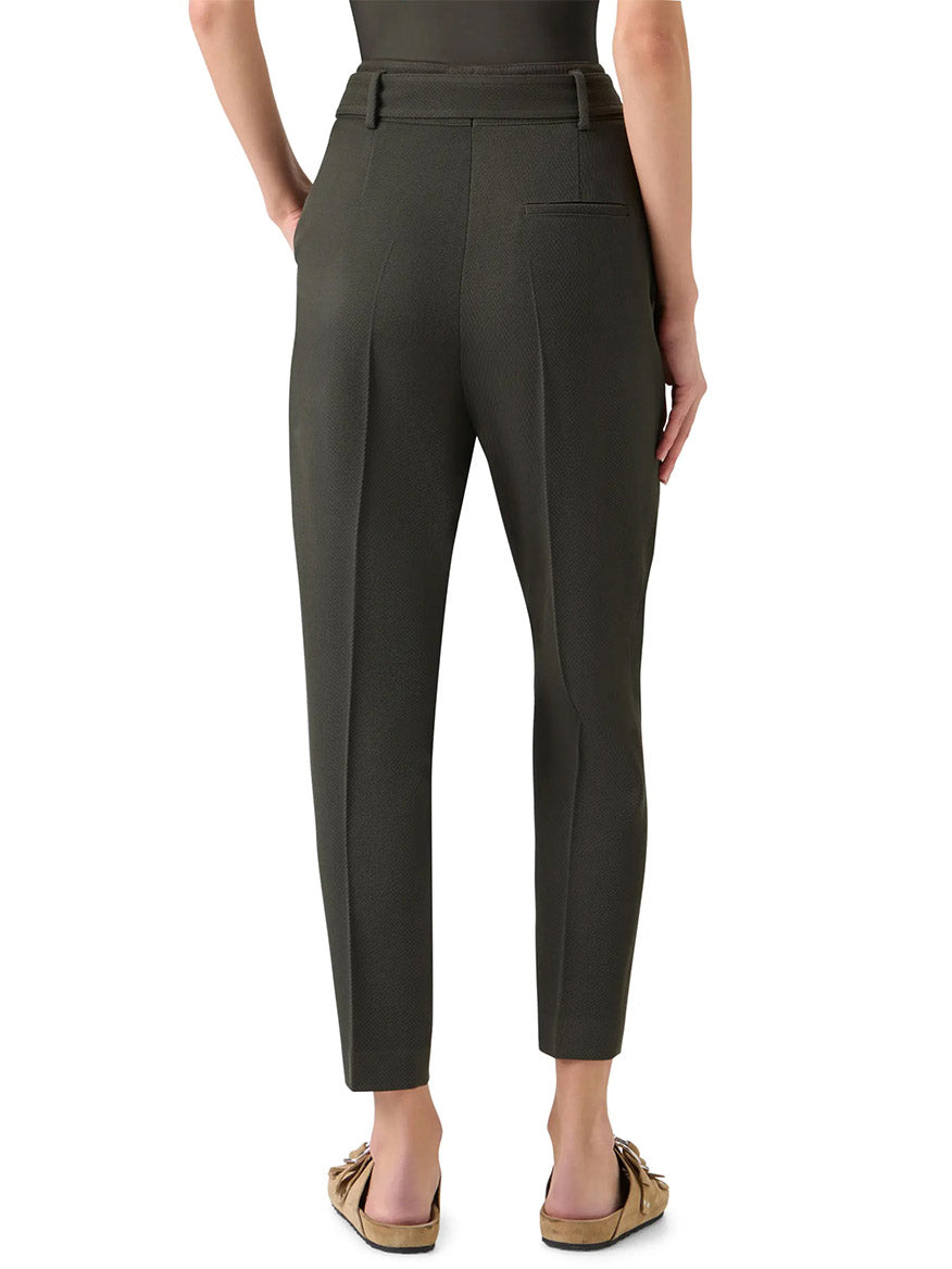 A person shown from the back wears Akris Punto Fred Belted High Rise Ankle Pants in olive, featuring a tapered silhouette and belt loops, paired with flat shoes.
