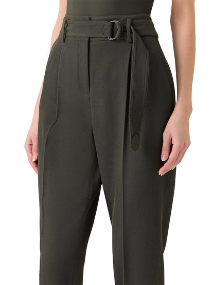 A person wearing the Akris Punto Fred Belted High Rise Ankle Pants in Olive, featuring a belted waist, side pockets, and a tapered silhouette from waist to mid-thigh.